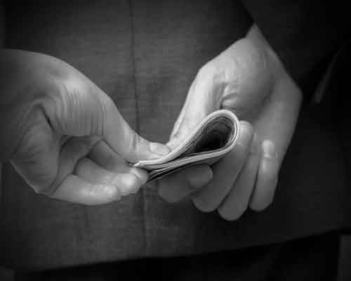 image of roll of money exchanging between two hands